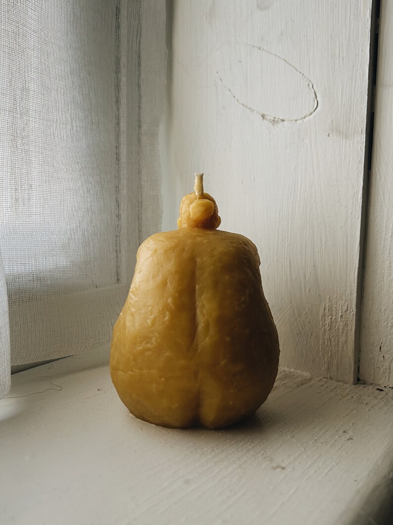 May include: A yellow pear-shaped candle with a textured surface.