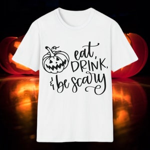 May include: White t-shirt with a black and white graphic of a pumpkin with a face and the text "eat, drink, & be scary".