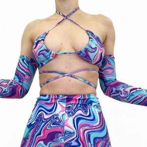 May include: A blue, pink, and purple swirl print halter top with matching shorts and arm warmers. The fabric has a glittery finish.