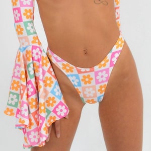 May include: A white bikini bottom with a colorful daisy print. The bikini bottom has a high leg cut and a low rise.