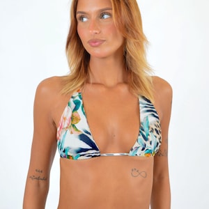 May include: A triangle bikini top with a floral and animal print design. The top features a mix of white, blue, pink, and green floral patterns, along with a leopard print. The halter straps are white.