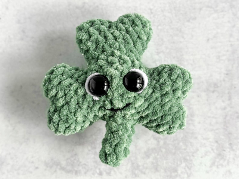 May include: A green crocheted shamrock with googly eyes and a smiling mouth.