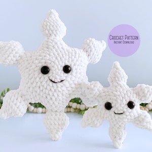 May include: Two white crocheted snowflakes with black button eyes and smiling mouths. The larger snowflake is in the foreground and the smaller snowflake is behind it. The snowflakes are on a light blue background. Crochet Pattern Instant Download.