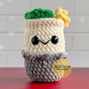 May include: Crochet pattern for a cute, amigurumi cactus with a green top, white body, and gray pot. The cactus has black eyes and a smiling mouth. The pattern is available for instant download.