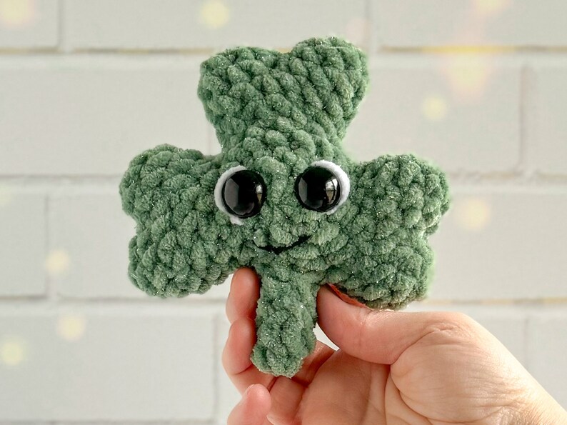 May include: A green crocheted shamrock with googly eyes and a smiling mouth.