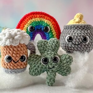 Puede incluir: Un conjunto de cinco juguetes de peluche tejidos a crochet, que incluyen un arcoíris, una jarra de cerveza, una olla de oro y dos tréboles. Los juguetes tienen ojos saltones y caras sonrientes.
