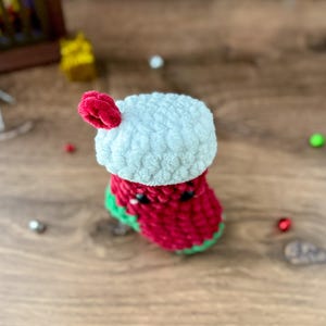 K&ouml;nnte beinhalten: Eine handgefertigte geh&auml;kelte Weihnachtsstrumpf in Rot, Wei&szlig; und Gr&uuml;n. Der Strumpf hat eine wei&szlig;e Manschette und einen roten K&ouml;rper mit gr&uuml;ner Bord&uuml;re. Ein kleiner roter Bommel ist an der Manschette befestigt. Festliche Weihnachtsdekoration.
