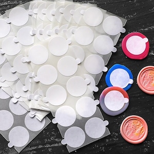 Può includere: Un foglio di cerchi adesivi trasparenti, perfetti per l'artigianato o progetti fai-da-te. Il foglio contiene più cerchi, ognuno con un retro adesivo bianco. Il foglio è circondato da cerchi di vari colori, tra cui rosa, blu e arancione.