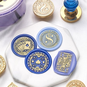 May include: Four blue and purple wax seals with gold lettering and designs. The seals feature a pair of playing cards, a dollar sign, a playing card, and the number 100.