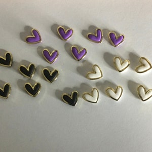 May include: Assortment of heart-shaped buttons in purple, black, and white with gold trim.