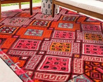 May include: A colorful rug with a geometric pattern in shades of pink, orange, black, and white. The rug has a traditional, tribal design.