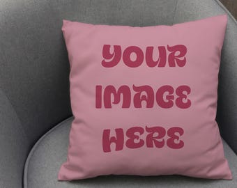 May include: A square, pink pillow with the words "YOUR IMAGE HERE" in a retro font. The pillow is resting on a gray armchair. The text is in a darker shade of pink.