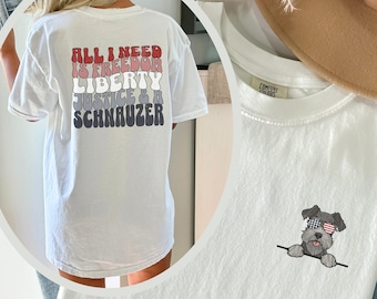 May include: White t-shirt with a graphic print of the text "ALL I NEED IS FREEDOM LIBERTY JUSTICE & SCHNAUZER" in rainbow colours. The shirt is oversized and the model is wearing it several sizes up.