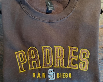 May include: Brown sweatshirt with a gold embroidered "PADRES SAN DIEGO" logo.