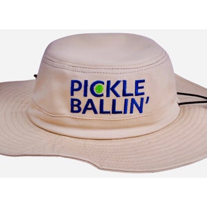 May include: A beige sun hat with a blue and green embroidered logo that says "PICKLE BALLIN'" on the front.