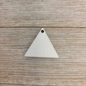 May include: White wooden triangle with a hole at the top. The triangle is on a wood background.