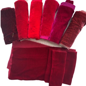 May include: Assortment of red velvet fabric scraps in various shades of red. The fabric is soft and luxurious, perfect for crafting projects.