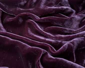 May include: Close-up of a deep purple velvet fabric with soft, flowing folds and a luxurious texture.