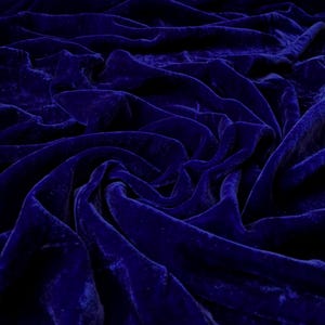 Könnte beinhalten: Nahaufnahme eines tiefblauen Samtstoffes mit weichen, fließenden Falten und einer luxuriösen Textur.