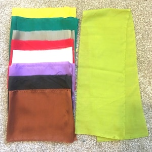 May include: A stack of eight fabric squares in different colors, including yellow, green, gray, red, white, purple, black, and brown. A single, larger square of lime green fabric is to the right of the stack.