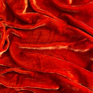 Może przedstawiać: Zbliżenie na bogaty, rdzawo-brązowy materiał welurowy o miękkich, falujących fałdach i luksusowej fakturze.
