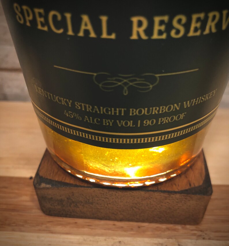 May include: A dark green bottle of Kentucky Straight Bourbon Whiskey, labelled "Special Reserve." The label indicates 45% alcohol by volume and 90 proof. The bottle rests on a small, square wooden coaster.