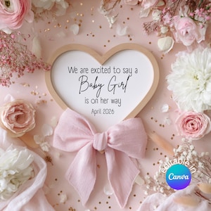 May include: A pink and white announcement card with the text "We are excited to say a Baby Girl is on her way April 2026." The card is heart-shaped and surrounded by pink flowers and a pink bow.
