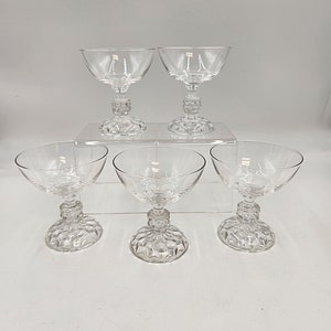 May include: Set of five clear glass champagne coupes with a diamond-shaped pattern on the base.