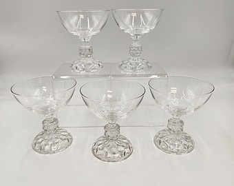 Pode incluir: Conjunto de cinco taças de champanhe de vidro transparente com um padrão de diamante na base.