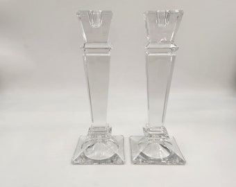 Könnte beinhalten: Ein Paar durchsichtige Kerzenhalter aus Glas mit quadratischer Basis und einem hohen, rechteckigen Körper. Die Halter haben ein schlichtes, elegantes Design.