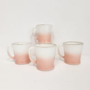 Pode incluir: Conjunto de quatro canecas vintage de vidro de leite com um design degradê rosa. As canecas têm uma parte superior branca que desbota para um rosa claro na parte inferior.