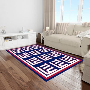 May include: A blue, red, and white area rug with the New York Giants logo repeated throughout. The rug has a red and white border.