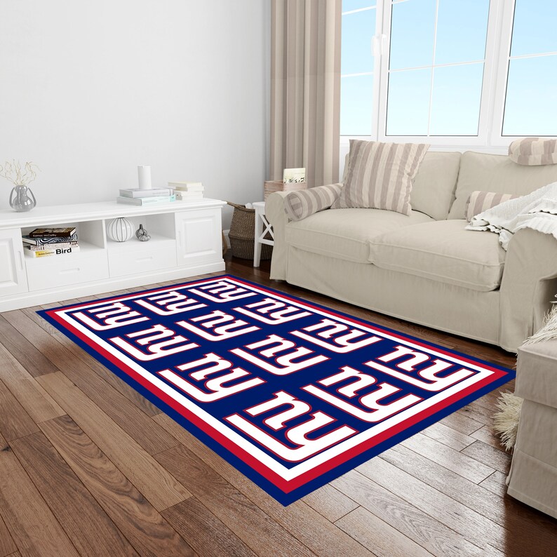 May include: A blue, red, and white area rug with the New York Giants logo repeated throughout. The rug has a red and white border.