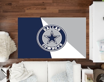 Puede incluir: Una alfombra de área azul marino y gris con un logotipo blanco de Dallas Cowboys en el centro. El logotipo presenta una estrella blanca dentro de un círculo gris con las palabras "Dallas Cowboys" alrededor del círculo.
