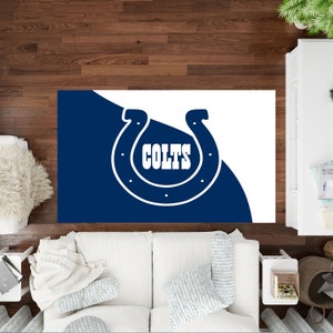 Puede incluir: Una alfombra blanca y azul con el logotipo de los Indianapolis Colts. El logotipo es una herradura blanca con la palabra "COLTS" en letras blancas dentro de la herradura.