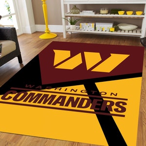May include: A yellow and burgundy rug featuring the Washington Commanders logo and the team name "WASHINGTON COMMANDERS" in black lettering.
