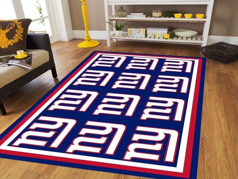 May include: A blue and red rug with a white repeated pattern of the New York Giants logo. The rug has a red and white border.