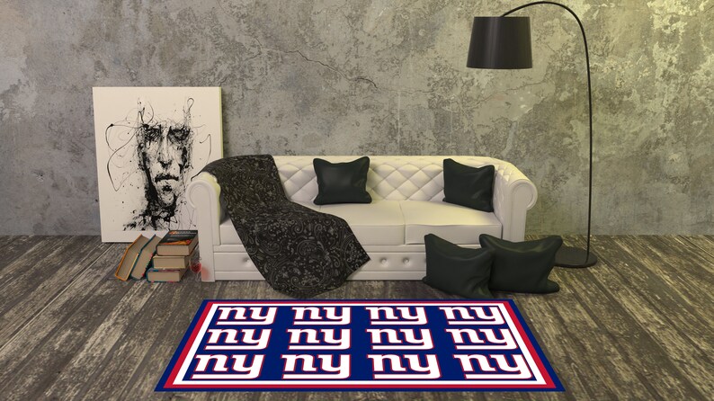 May include: A blue and red rug with the letters "NY" repeated in a grid pattern. The rug is in a living room setting with a white couch and black pillows.