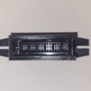 May include: A black plastic connector with eight pins. The connector has a rectangular shape and is designed for electronic devices.