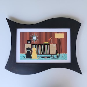 May include: A framed print featuring a retro-style illustration of a living room with a record player, a clock, and two dogs. The black frame has a unique, wavy design. The color palette includes brown, blue, and yellow.