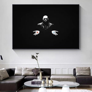 Puede incluir: Arte mural enmarcado en blanco y negro que representa a un hombre con un abrigo oscuro sosteniendo una pastilla roja y otra azul. El fondo es negro, creando un contraste dramático.