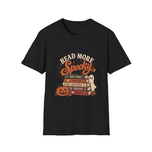 Puede incluir: Una camiseta negra de manga corta con un gráfico de una pila de libros etiquetados como Ghost Stories, Thrillers, Mysteries, Fantasy y Romance. El diseño incluye una calabaza de Halloween, un fantasma y el texto Read More Spooky en naranja.