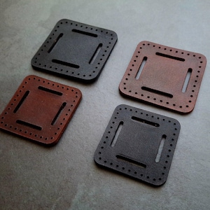 Può includere: Quattro quadrati di pelle con un design cucito. Due quadrati sono marroni e due quadrati sono neri.