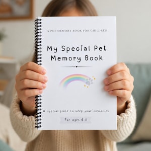 May include: A white spiral-bound pet memory book held by a person. The cover reads "My Special Pet Memory Book" with a rainbow and paw print design. Text at the top says "A PET MEMORY BOOK FOR CHILDREN" and at the bottom "A special place to keep your memories. For ages 6-11."