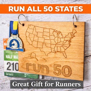 May include: Wooden plaque with a laser-etched map of the United States, the words "run 50", and the text "Run All 50 States". A Boston Marathon medal and a race bib are attached. The text "Great Gift for Runners" is at the bottom.