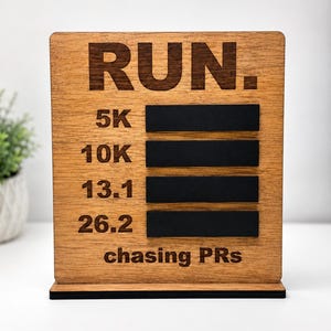 May include: Wooden running milestone sign with the word "RUN" at the top. Below are the distances 5K, 10K, 13.1, and 26.2, with black felt strips. The phrase "chasing PRs" is at the bottom. The sign is brown with a black base.