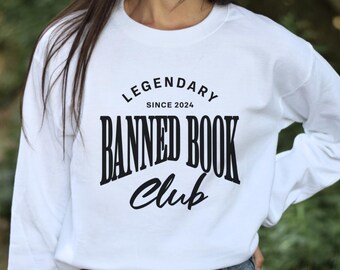 May include: White long-sleeve sweatshirt with a black circle graphic that says "Legendary Since 2024 Banned Book Club".