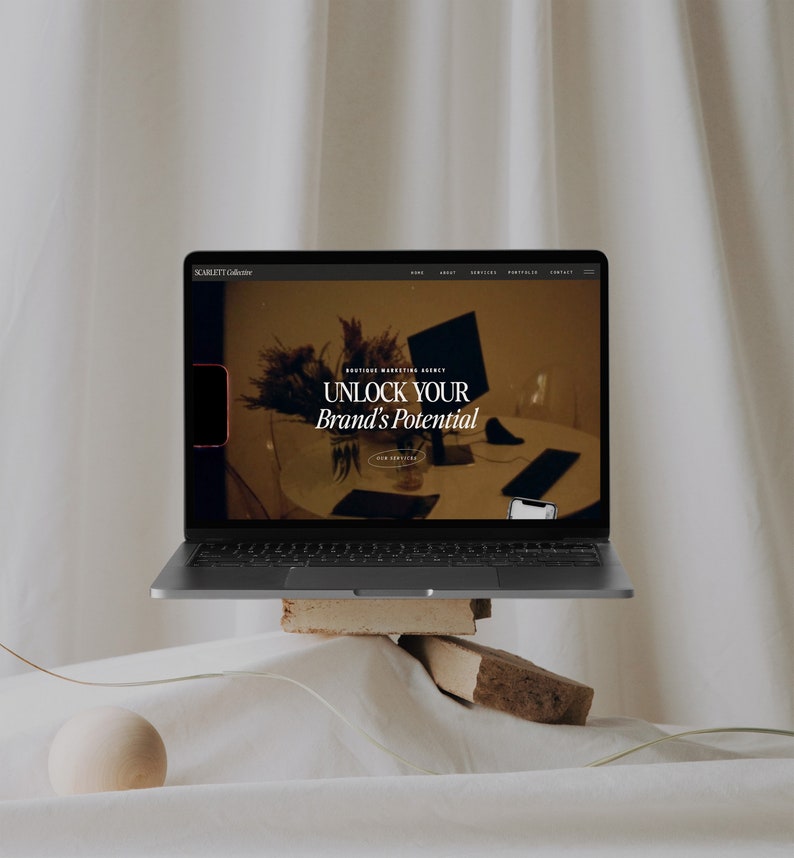 May include: A laptop computer displaying a website for Scarlett Collective, a boutique marketing agency. The website features the text "Unlock Your Brand's Potential".
