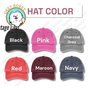 May include: A display of six baseball caps in various colors: black, pink, charcoal grey, red, maroon, and navy. Each cap has the color name printed on it in white. The image also includes a logo with a cartoon dog.