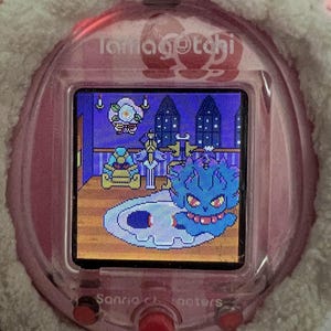 Puede incluir: Una mascota digital Tamagotchi rosa con una funda blanca y esponjosa. La pantalla muestra una escena pixelada con un personaje azul con forma de fantasma. El texto "Sanrio characters" es visible en el dispositivo.